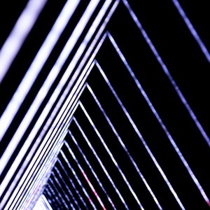 A photo of a light triangular light sculpture. A series of triangles is each lit up in white and bright colours. The triangles recede in to the distance.