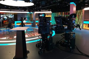 The Bloomberg TV studio. There are several large cameras pointed at a desk, and several large LED displays.