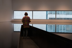 A woman in a check shirt overlooks a still tank of black oil.