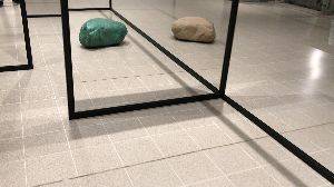 A video of WeltenLinie by Alicja Kwade. As the camera pans across a tiled floor, a large stone on the floor appears to change colour.