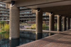 A photo of a Barbican walkway with a pond in the foreground.