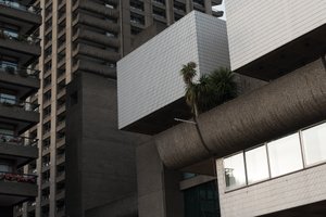 A photo of the a corner of The Barbican Centre with several tower blocks in the background.
