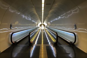 A photo looking down a long corridor with two moving walkways on either side.