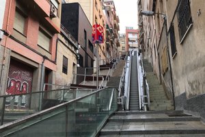 A photo looking up a steep street / alley in Barcelona. There’s an open-air escalator in the middle and steps either side.