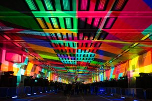 A photo looking straight down the covered Beech Street. The entire ceiling is covered with a patchwork of bright projected colours.