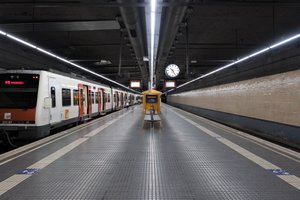 Looking straight down a train platform, with tracks on either side. There’s a train on the left hand side.