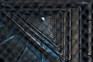 Looking up the void of a staircase through a metal grate. The void is triangular.