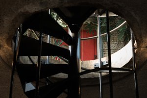 Looking up a spiral staircase at the level above. There’s a red door in the distance.