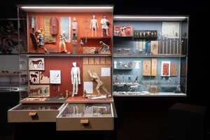 A photo of a display case showing many small models of people and various tools. The models are for use in historical dioramas.