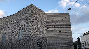 A video shot from the exterior of the Kunstmuseum. The building has a massive sign built in to the brickwork. As the video progresses, words appear on the side of the building and scroll along.