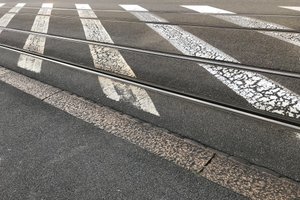 A photo of tram tracks and painted white stripes on a stretch of road.