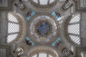 A wide photo of the main ceiling dome in the Museu Nacional d’Art de Catalunya. There’s intricate murals in the centre, and arches of windows on all four sides.