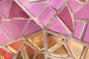 A close up of some tiled mosaic on the exterior of la Sagrada Família. The tiles are arranged in five segments like a pie chart. The top three segments are pink, and the bottom two are gold.