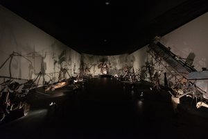 A dark room filled with many eery metallic sculptures by Jean Tinguely.