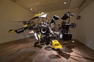A large mechanical metal sculpture in a room - made from several car parts.