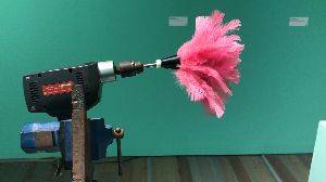 A video of a pink dusting brush attached to the end of an electric drill. As the vide plays, the drill turns on, and the brush spins around.