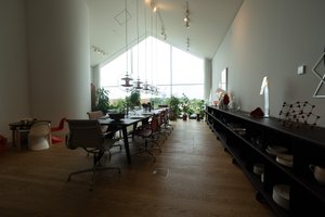 Looking towards a window inside the Vitra showroom. The room has a profile like a house with a pointed roof. Inside the room is a long table and bench.