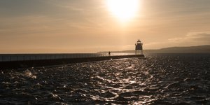 A pier receding in to the distance with a lighthouse at the end.