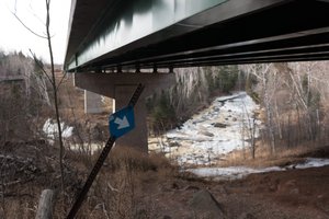 A photo taken from under highway 61 as it passes over the Baptism river. There’s a blue arrow pointing to the right.