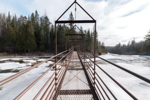 A photo taken from a steel footbridge over Baptism river. The camera is facing directly down the bridge.