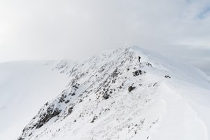 Ed in the distance looking down over a snow covered ridge.
