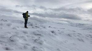 Walking on the plateau of Mullach nan Coirean. The top has crunchy snow as Ed walks towards Chris in the distance.