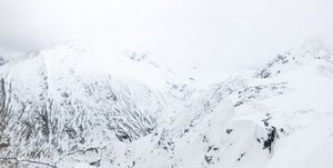 A panorama of a white mountainside, with occasional dark patch of rock.