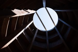 Looking up to a circular opening in a wooden roof.