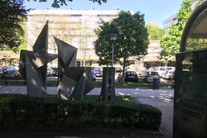 A concrete sculpture at the side of the road. The sculpture resembles origami with lots of folded corners.