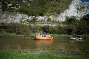 A small faded orange life raft moored on the side of the river Ouse.