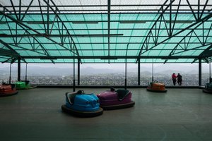 Bumper cars sit unused at the top of a mountain. In the background the city of San Sebastián can be seen below.