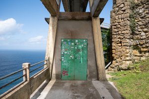 Looking straight on to a green doorway. The door is covered in stickers and graffiti.