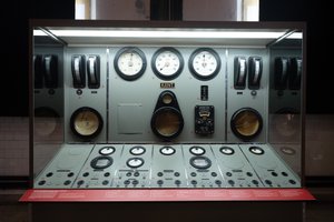 Looking straight on to a large control panel in Maat. The panel has a several columns of controls and dials and has a light grey-green surface colour.