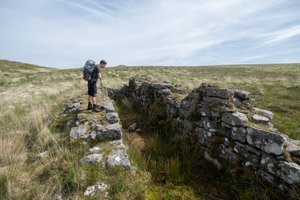 Oliver Wooderson stands on the ruin of a building wall looking in to the inside of the ruin.