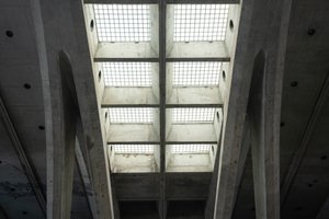 Looking up at skylight windows in a train station. The ceiling is cast concrete, and the lights are made from a grid of glass tiles.