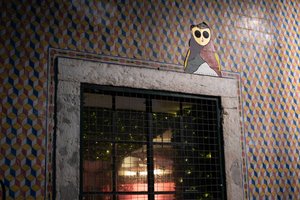 A photo of the top of an exterior window. The wall has a small decorative tile pattern and a graphic of a small person is stuck on the top right of the window.