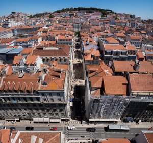 A square panorama looking down from high up to the streets of Lisbon. Down the centre of the frame a pedestrian street recedes. At the bottom of the frame is a large road.