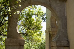 Looking through a circular arch between two pillars to some trees beyond.