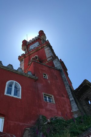 Looking up at a tall ornate red building in Pena palace.