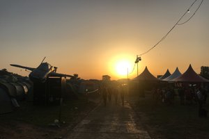 Sunset over Glastonbury. There’s tents on the right and a plane on the left.