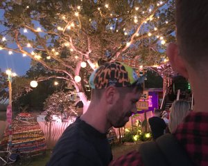 James and Oj face away from the camera under at night under a lit tree.
