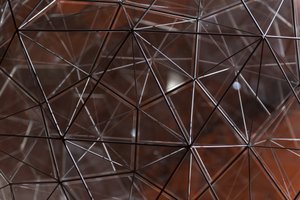 A close photo of many connecting metal rods making a 3d geometric shape.