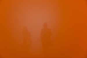 A deep orange frame with no distinct features. Two bodies can just be seen in the background.