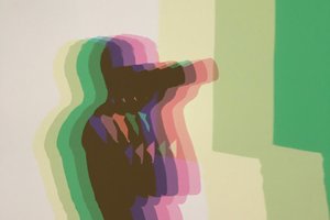 The shadow of Ed Horsford taking a photo with a large camera. His shadow is made up of multiple different colours from light yellow through to green and pink.