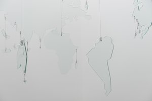 A large mobile made from sheets of glass cut in to shapes of continents, forming a glass map of the world.