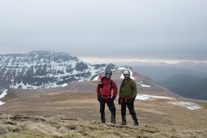 Chris and Ed pose for a photo on top of Beinn Eighe. They both have heavy jackets and helmets on.