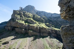 A photo taken from one side of a valley facing the other. The opposite face is deeply scarred, with patches of moss green on the upper faces.