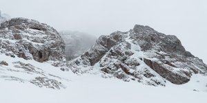 Some large rocky hills near Ben Nevis. They’re covered in snow and ice, and you can just make out small coloured figures dotted around them - people climbing the ice.