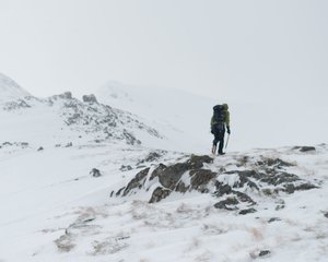Chris walking ahead up a snowy mountain - there’s low visibility and a few flakes of snow in the air.