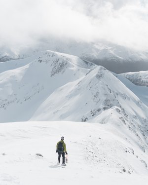 Chris walking ahead of camera, with several snowy mountains ahead of him.